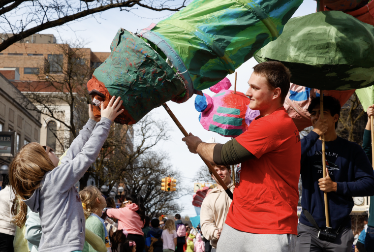 A UM student engaging with audience members through their giant puppet during the FestiFools parade!