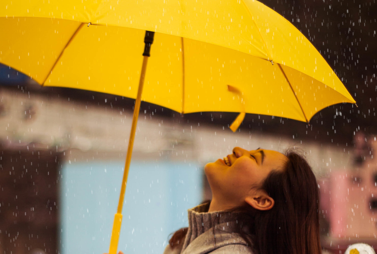 Person standing under an umbrella smiling