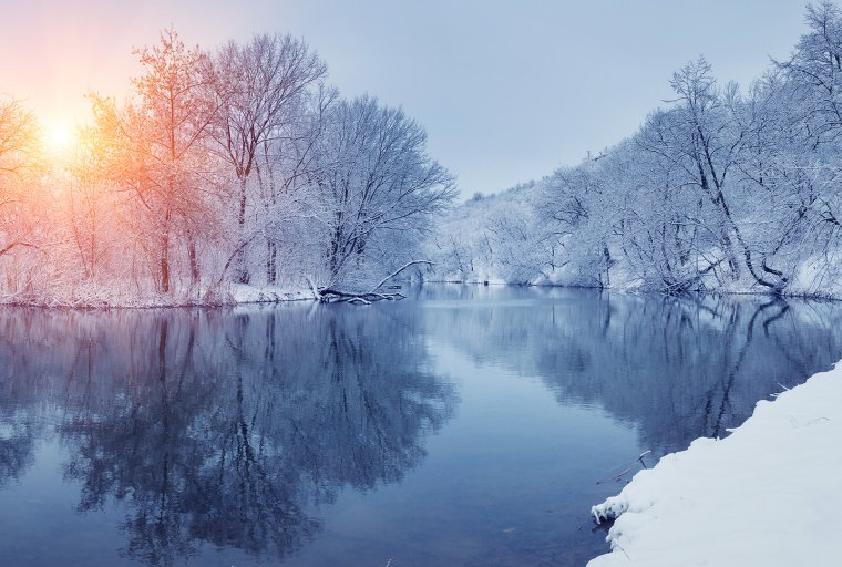winter sunrise through trees and over a snowy river
