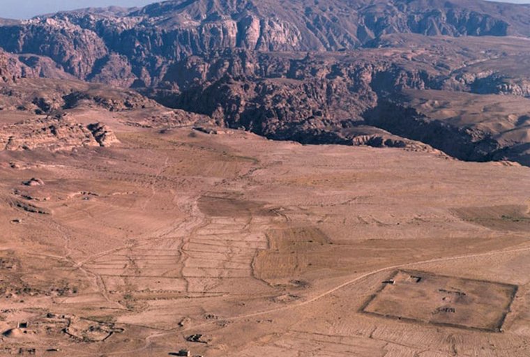 Overview of the archaeological site of Humayma, an ancient settlement in Jordan, with mountains rising in the background.