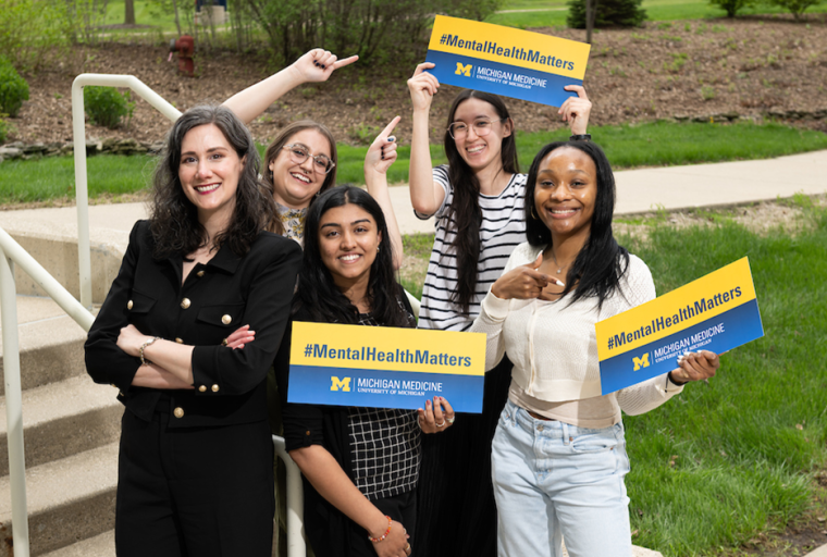 A group pf people holding "mental health matters" signs and smiling