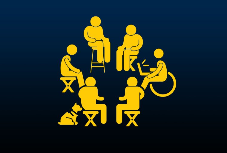 6 people sit in a circle on various chairs and assistive devices. 1 person has a service dog and another holds a laptop.