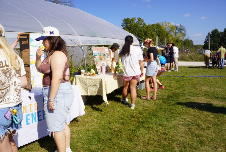Organizations tabling on a sunny day in front of a hoop house
