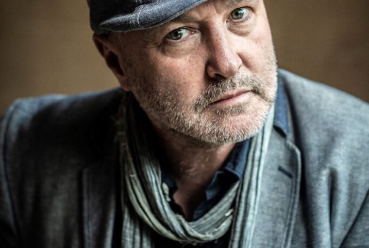 Colum McCann (headshot) in cap, scarf and sport coat.