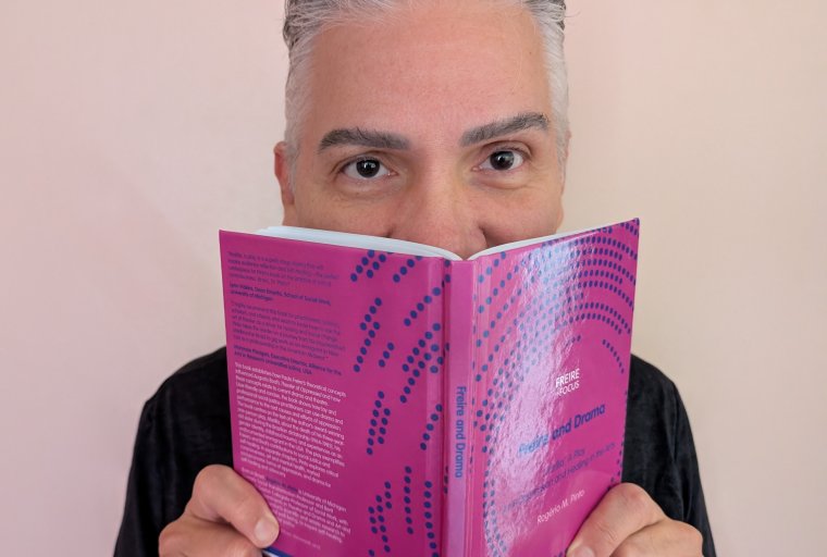 Person looking up behind a magenta book cover.