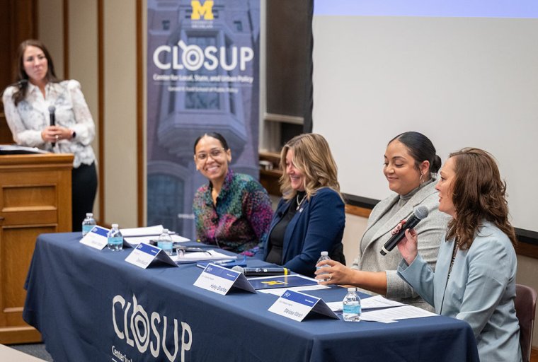 Panel of four female speakers in front of M CLOSUP banner.