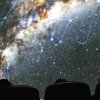 Visitors at a planetarium show looking up at the lighted dome.