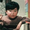 A film still of a young Japanese boy making the "ok" sign in a 1950s-style room