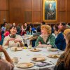 Students sitting at a round table sharing a meal and laughing together.