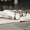Glasses rest on top of notebook on desk.