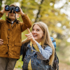 A mother pointing and son using binoculars to look at nature