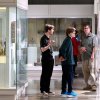 A family of visitors pauses between the Dynastic and Graeco-Roman Egyptian galleries at the Kelsey Museum. Displayed in a case to their left are several small Egyptian artifacts, including bronze figurines of deities and faience ushabtis.