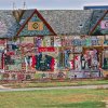 A colorful, two-story building covered in intricate mosaics, beads, vibrant artwork, and painted text.