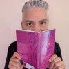 Person looking up behind a magenta book cover.