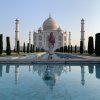 A young woman standing in front of the Taj Mahal with a pink scarf wraped around her shoulders and head