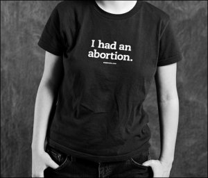 An Individual in a black shirt that says " I had an abortion".