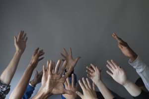 a group of people hold their hands upward