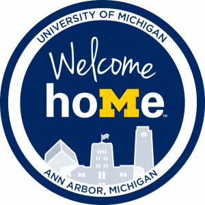 Blue circle with "Welcome Home" written in the middle above the skyline of the Michigan Union