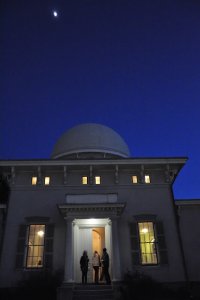 Peoplo entering the Detroit Observatory in the evening with the Moon over the dome.