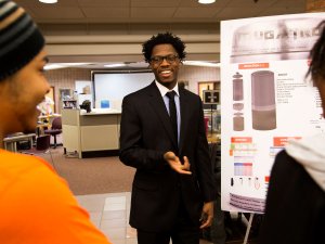 Nelson Jenkins, ME BSE Student, explains his group's project, Mugatron, to Wayne Lester, CoE First-Year Student, and Sydney Williams, AERO BSE Student, at the Multidisciplinary Design Expo. Photo: Joseph Xu, Michigan Engineering Communications & Marketing.