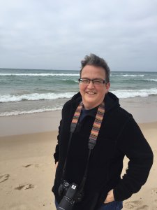 An image of Professor Jackie Rhodes at the beach with a camera