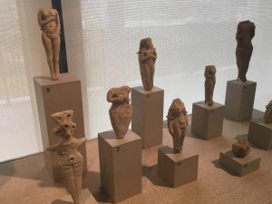 A collection of small female figurines made of pale clay.