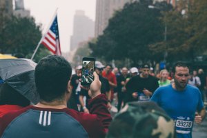 A marathon spectator films runners as they near the north east corner of Central Park in Harlem just before entering the last leg of the New York City Marathon on November 5th, 2017.