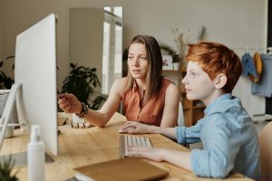 A parent helps her son with online classes
