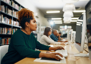 Black female student looking focused at computer in library