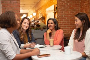 4 women around a table talking and networking