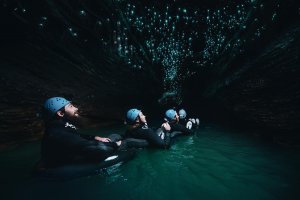 Lecture image - four people floating in a dark cave with bioluminescence above.