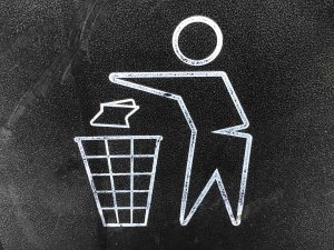 Close up of a recycling bin logo, with a person throwing paper into a bin.
