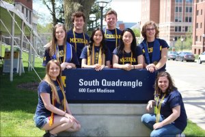 Group of graduating Honors students, with Honors cords, gathered around South Quad sign.