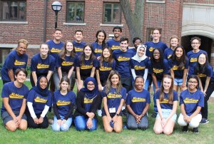 Large group photo of college students and program staff, all wearing matching blue t-shirts