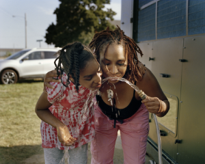 Two black women drinking from a garden hoes