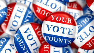Collection of red, white, & blue button with phrase, "Your vote counts" printed on them. [Credit: Shutterstock]