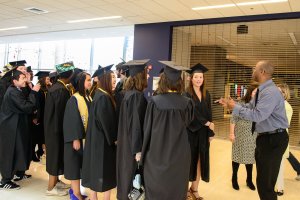 Brian Banks talks to a line of students, wearing caps and gowns, at commencement
