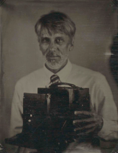 A photograph of a man holding a camera