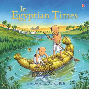 The cover of the book “In Egyptian Times” by Kate Davies and Alfredo Belli, showing two Egyptian children using a net to catch fish while on a vessel on a river. Buildings, palm trees, and pyramids are visible in the background.