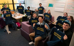 Students holding shirts that say "MICHIGAN FIRST-GENS" in the First-Gen Gateway space