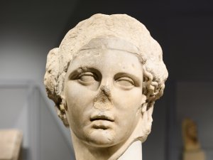 Front-facing marble head of Bacchus, whose nose is broken off.
