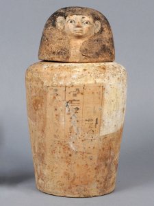 Canopic jar with a human head and hieroglyphics on the front of the base.