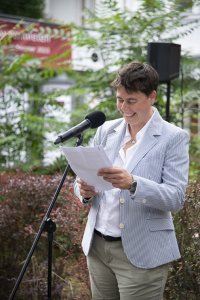 Woman stands outdoors in front of a microphone