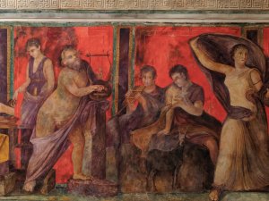 Section of the Kelsey Museum’s Villa of the Mysteries watercolor reconstruction showing a group of men (two of whom play a lyre and a pan flute), women, and goats.