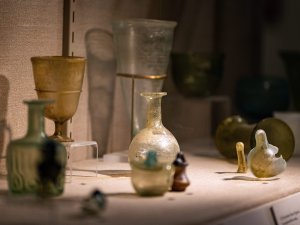 Kelsey Museum display showing green, white, and brown glass vessels of various sizes and shapes.
