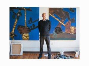 artist Enrico Riley standing in front of his artwork