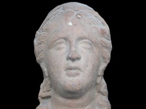 Ceramic votive head of a woman wearing earrings.