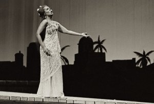 Image of Shirley Verrett, singing on stage with silhouette of palm trees in background