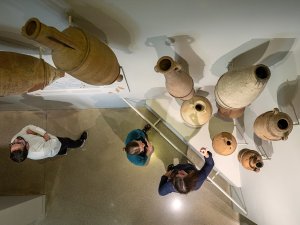 Visitors look up at a display of amphorae mounted on the wall at the Kelsey Museum.
