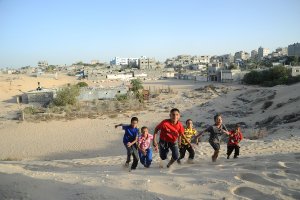 Children playing on one of the sand hills west of Khan Younis refugee camp, photo by Shareef Sarhan,  2015.